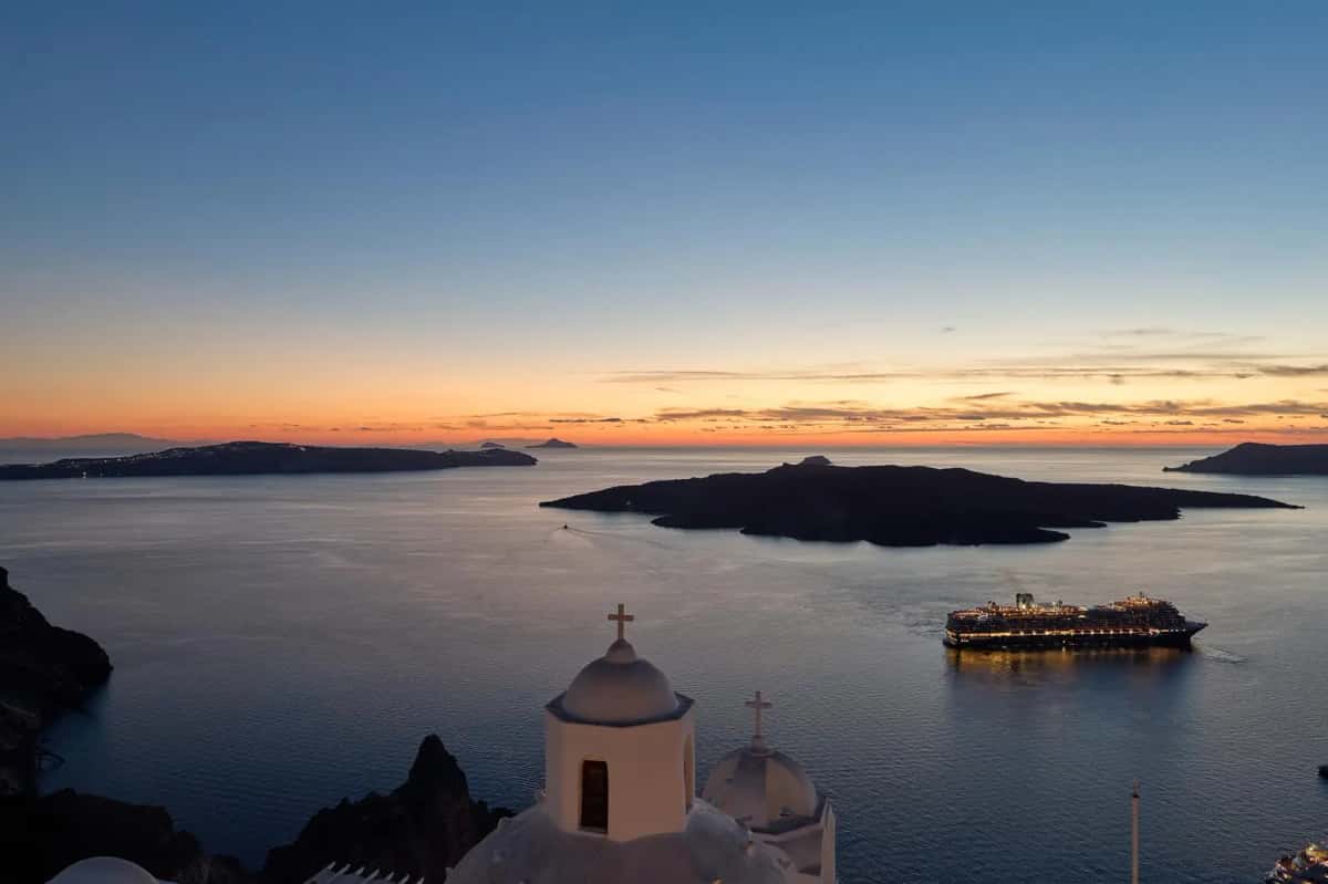 Santorini caldera sunset panoramic view with church dome and cruise ship